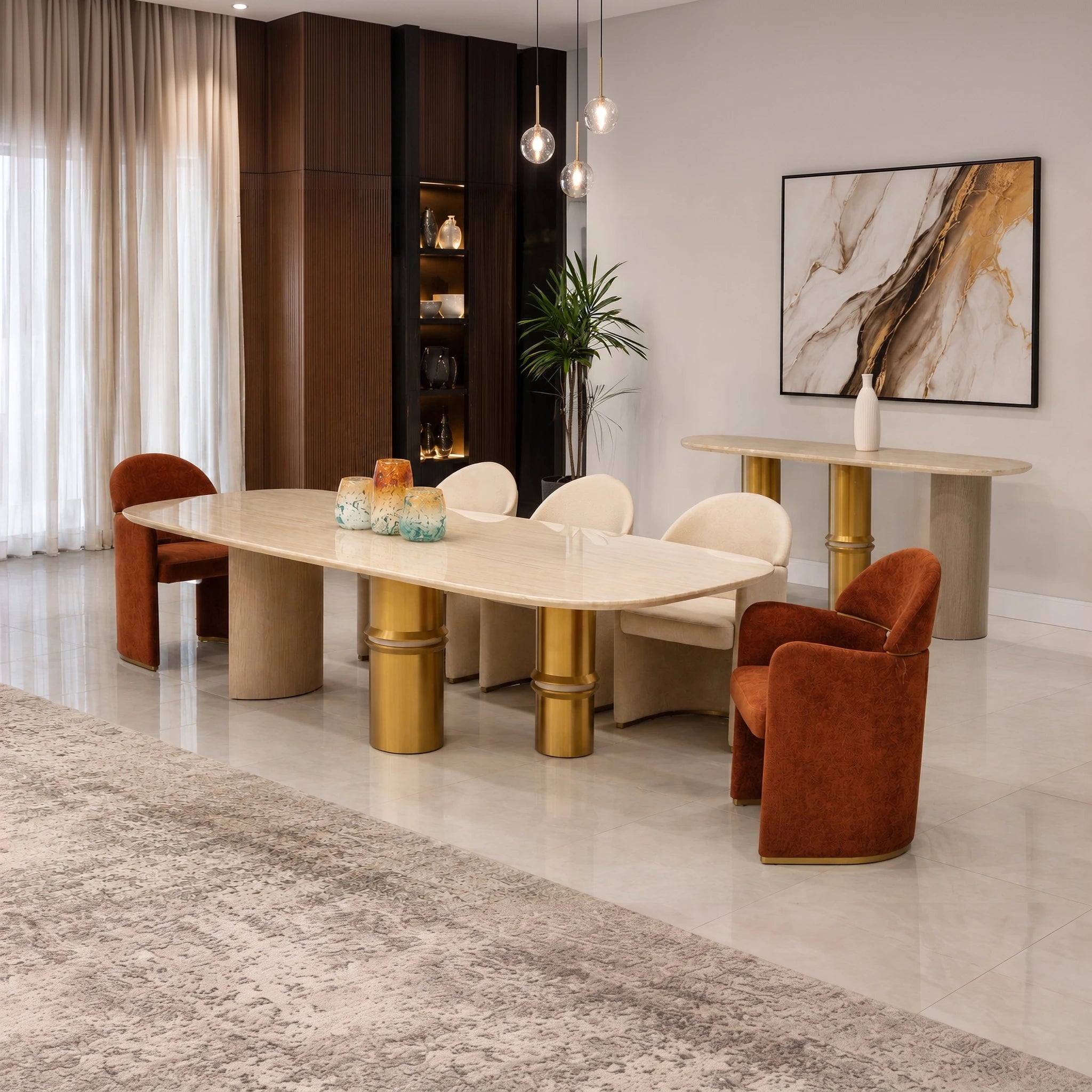 Bodrum dining room table with a polished marble top and gold pedestal legs, shown with rust-orange upholstered chairs in a