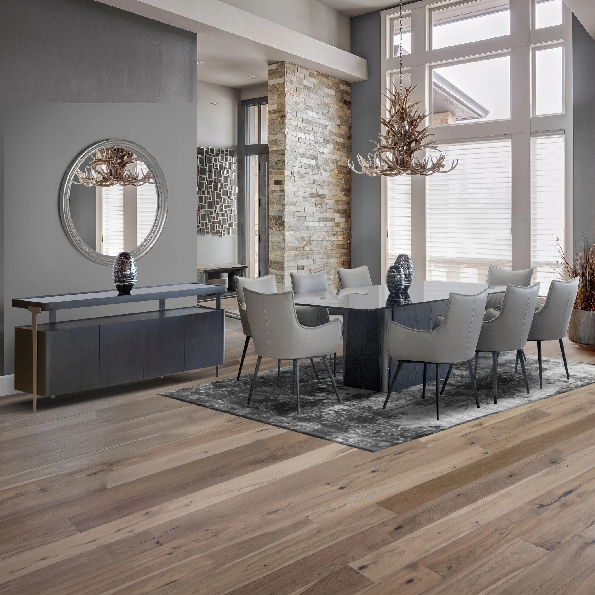 Sierra dining room table with a dark base and glass top, surrounded by light gray upholstered chairs in a modern dining room.