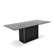 A rectangular Sierra Dining Room Table with a dark glass top and a solid, dark wood pedestal base, shown from an elevated