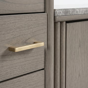 Tazmyn Sideboard in grey oak, close-up of wood grain drawer front with brushed brass handle and top edge