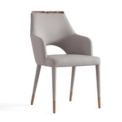 Light grey upholstered Umberto dining chair with armrests, a unique marble top accent on the back, and slender tapered legs.