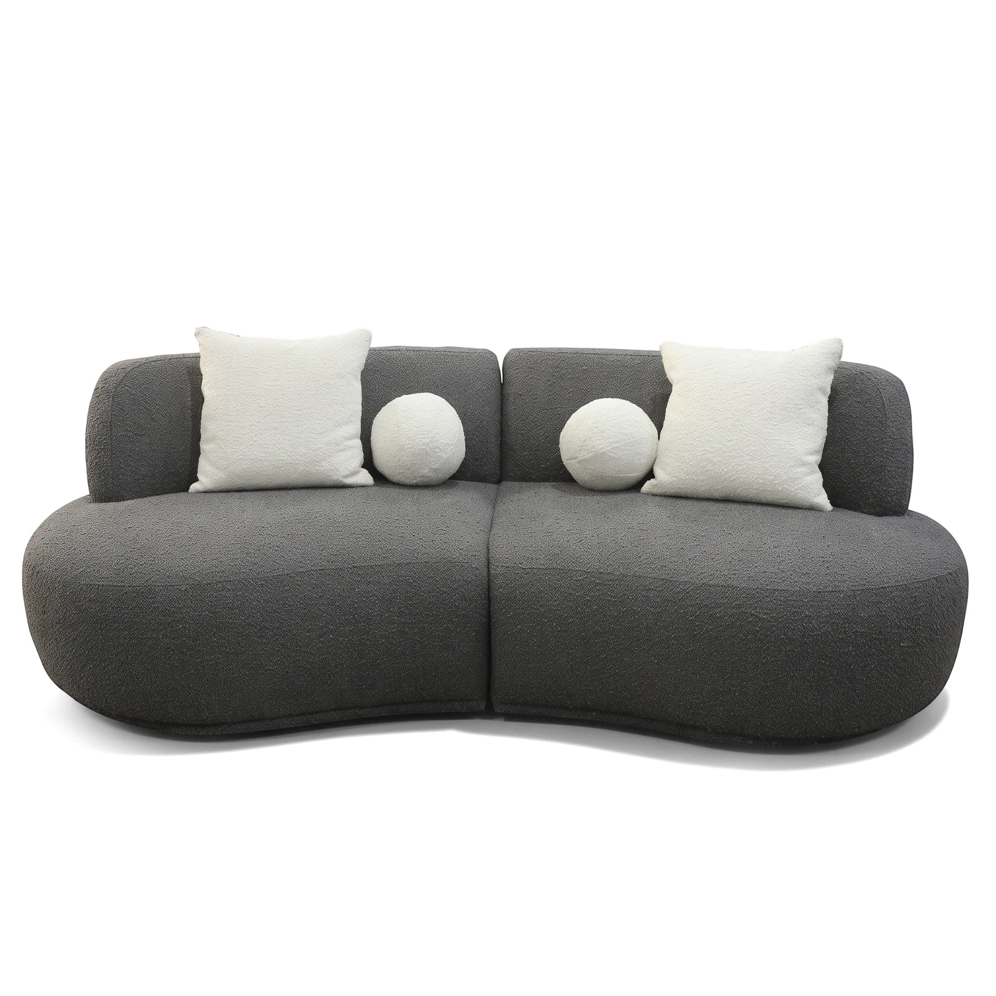 Dark grey textured Witney sofa with a modern curved design, featuring two square and two round white decorative pillows.
