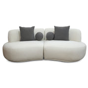 Modern white bouclé Witney Sofa featuring two curved sections and four dark gray throw pillows, viewed from the front.